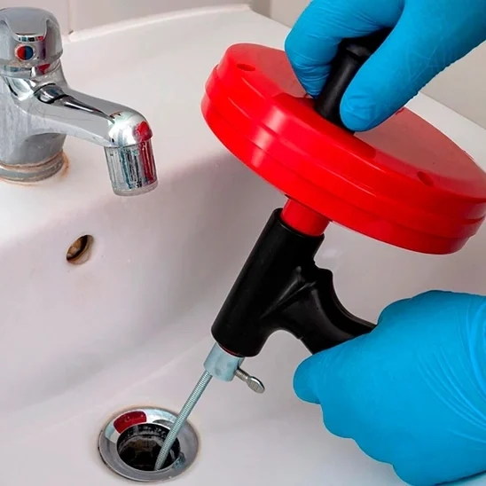 a plumber snaking a clogged drain