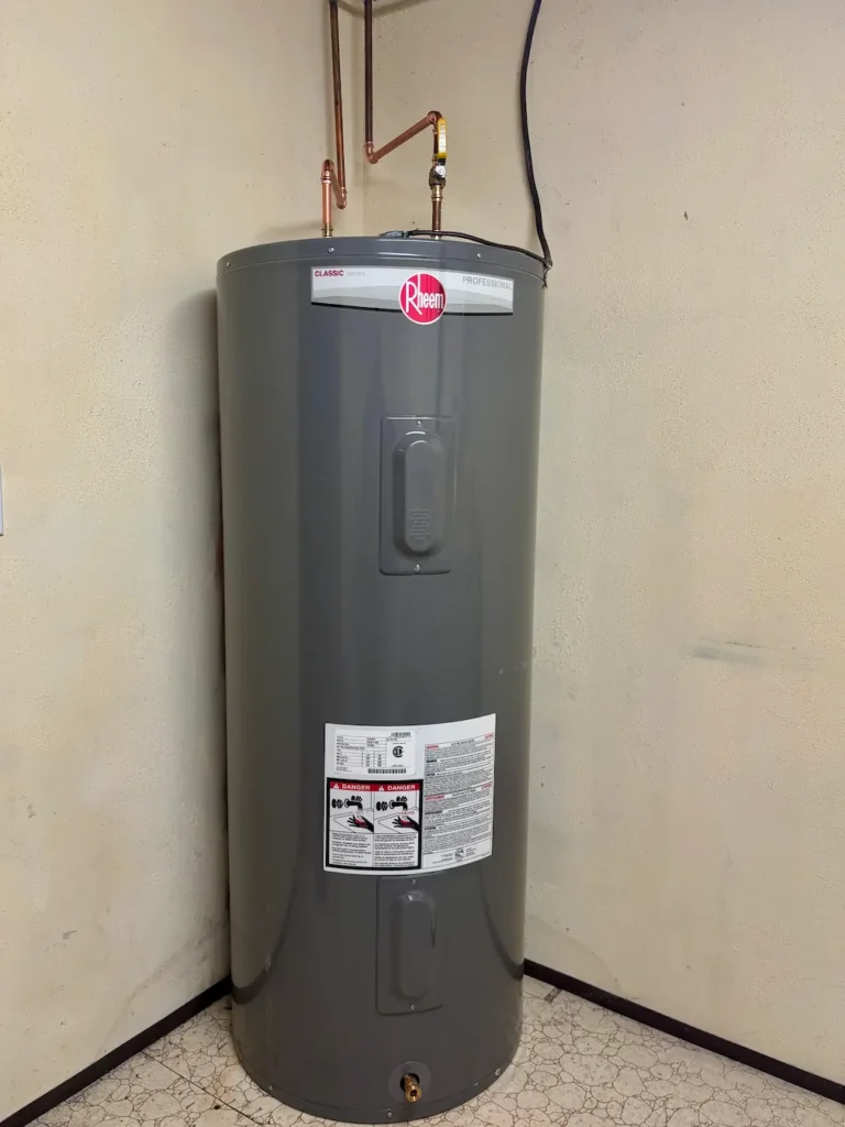 Rheem water heater installed against a wall with copper piping connected at the top